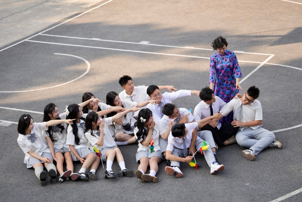 Seated students pointing playfully in a chain