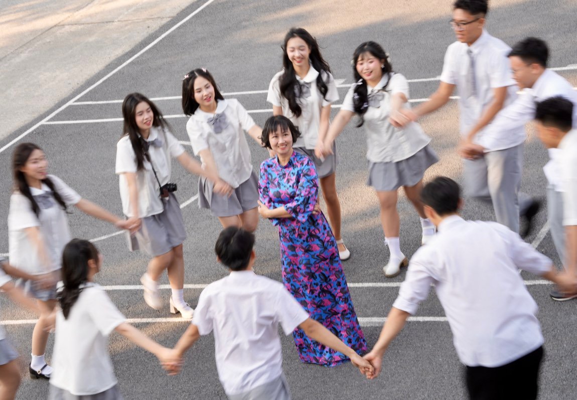 Students holding hands in a circle around their teacher