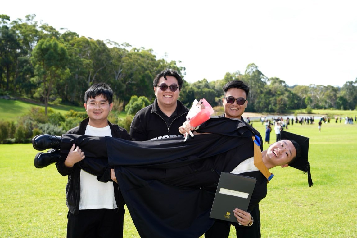 Friends carrying the laughing graduate in their arms