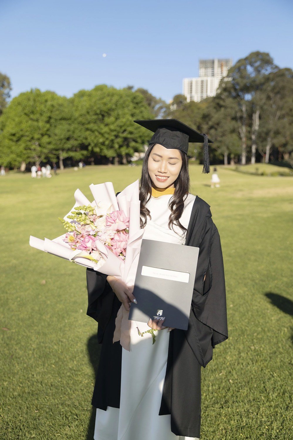 Graduate with a pastel bouquet in serene golden-hour light